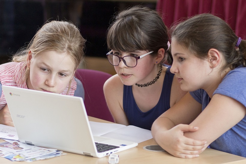 two girls smiling in front of computer